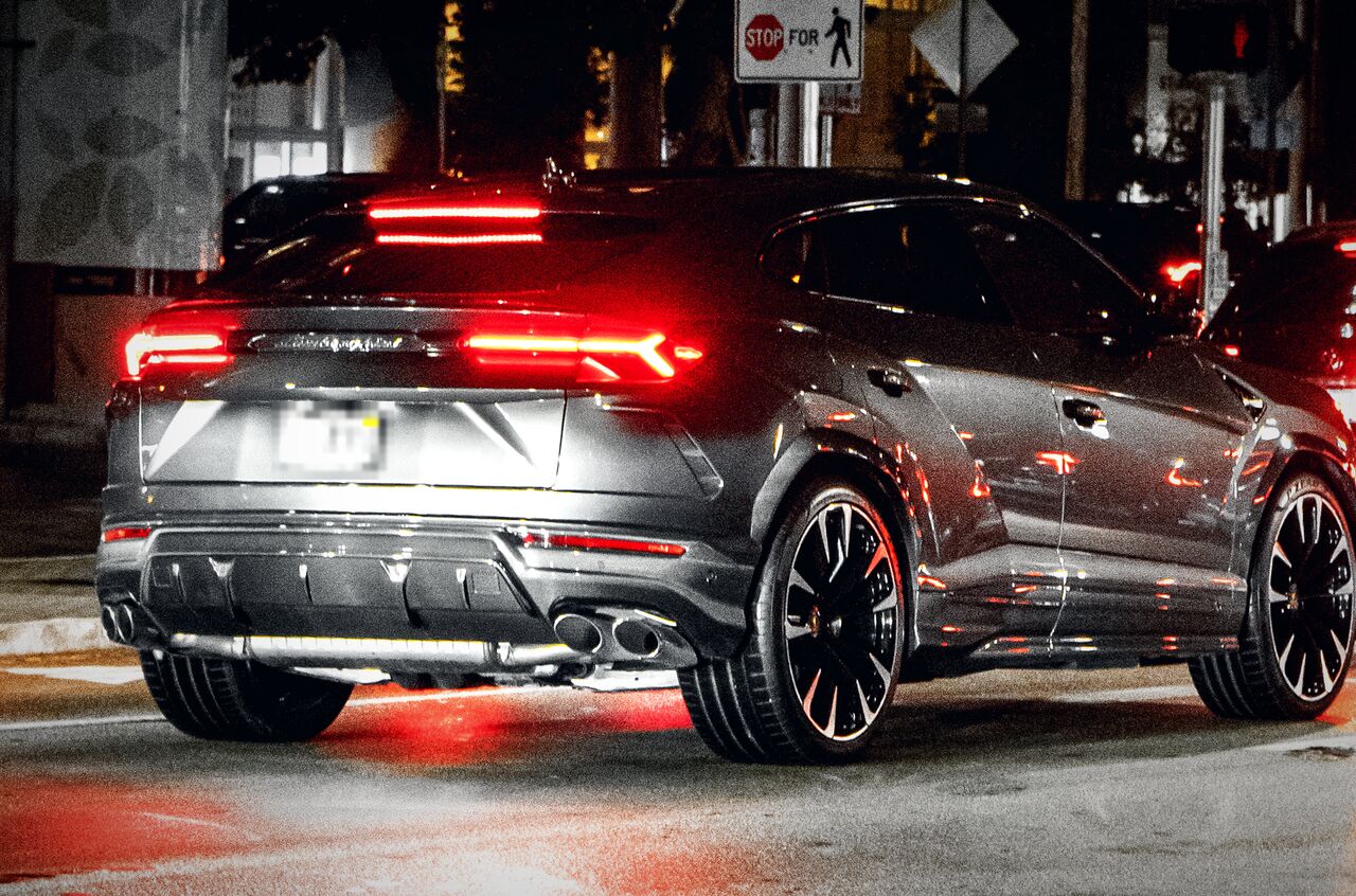 Traseira de um Lamborghini Urus cinza à noite, com as lanternas vermelhas acesas